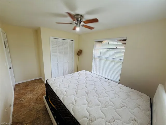 Neutral wall tones with a ceiling fan, window with horizontal blinds, and bi-fold closet doors