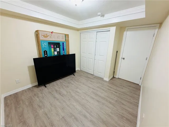 Wood-finish flooring with white trim, featuring a bi-fold closet with panel doors and a white painted door with a silver knob