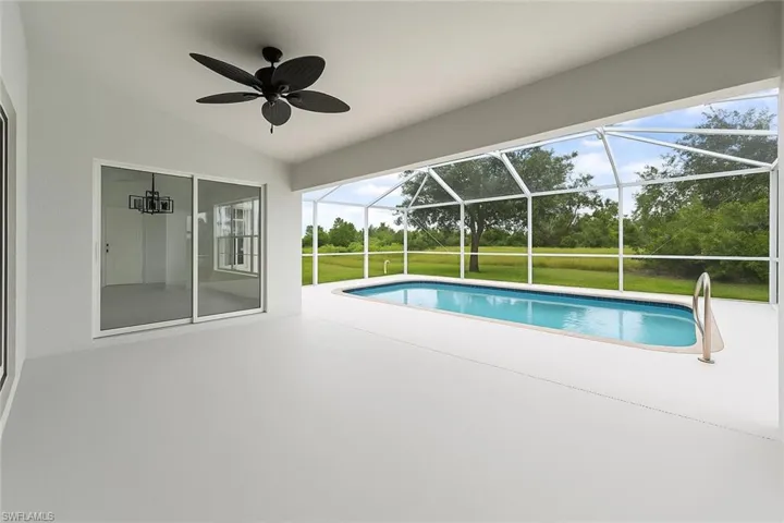Swimming pool featuring a sunroom, a patio, a lanai, a yard, and ceiling fan