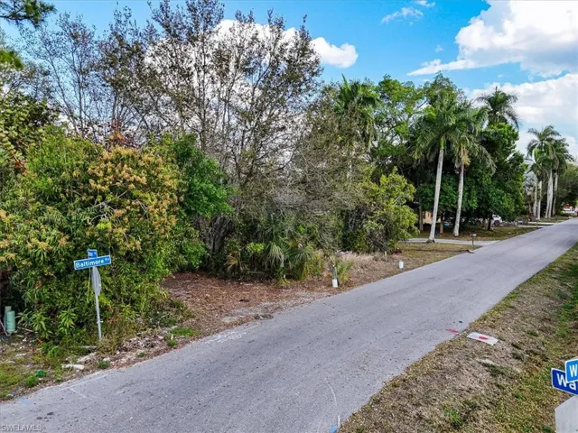 View of asphalt road featuring view of wooded area