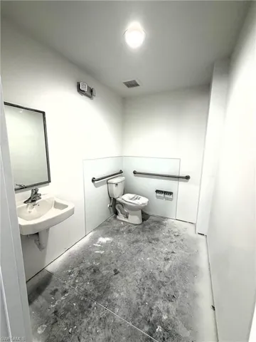 Half bath with toilet and concrete flooring
