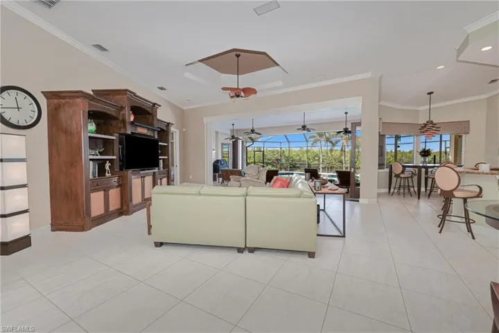 Living room featuring light tile patterned floors, ceiling fan, and ornamental molding