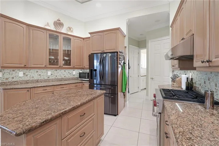 Kitchen with decorative backsplash, light stone counters, and appliances with stainless steel finishes