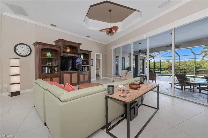 Tiled living room with a notable chandelier, crown molding, and a tray ceiling