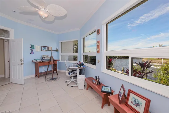 Tiled home office featuring ceiling fan, a water view, and ornamental molding