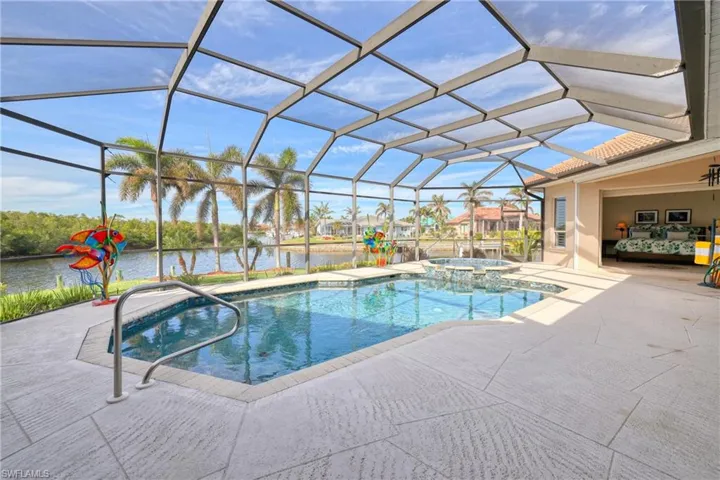 View of swimming pool with an in ground hot tub, a patio, a water view, and glass enclosure