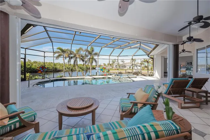 View of patio featuring a lanai, a pool with hot tub, a water view, and an outdoor hangout area