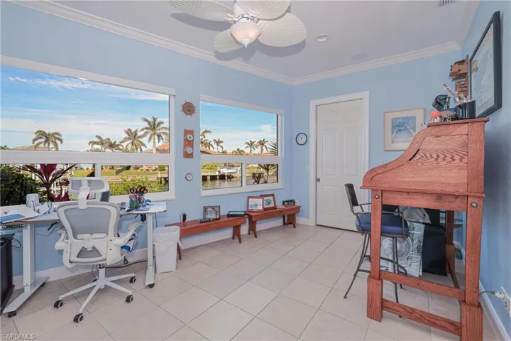 Office space with ceiling fan, light tile patterned floors, and ornamental molding