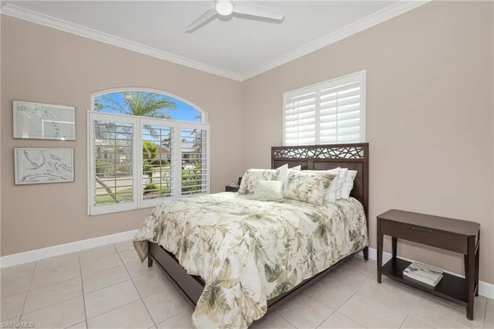 Bedroom with ceiling fan, light tile patterned floors, and ornamental molding