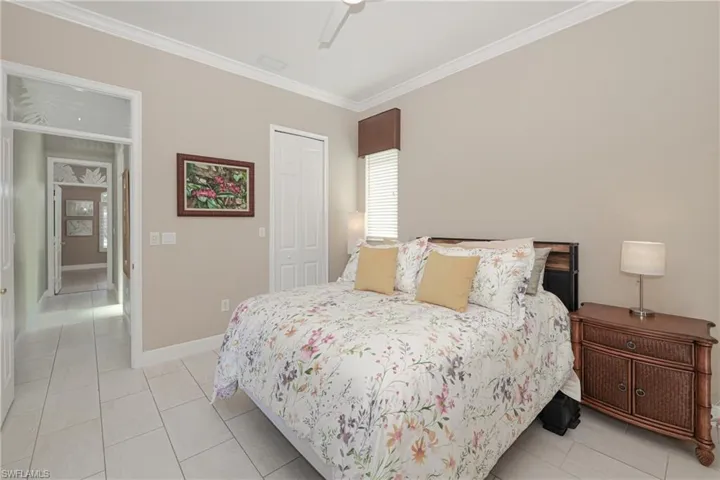 Tiled bedroom with ceiling fan, crown molding, and a closet