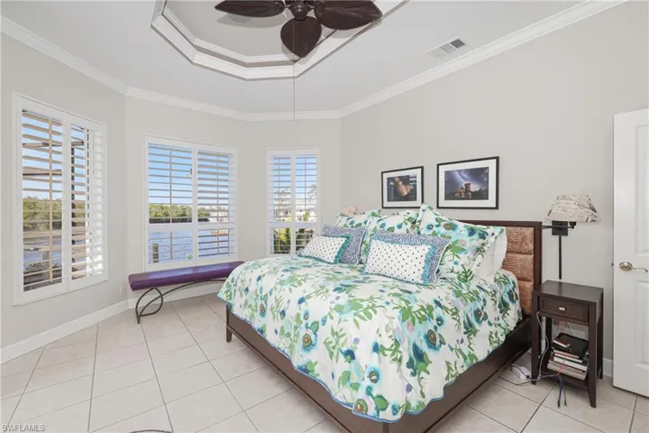 Bedroom featuring light tile patterned floors, ceiling fan, and crown molding