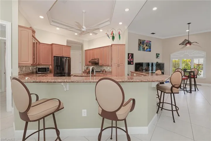 Kitchen featuring decorative backsplash, light stone counters, stainless steel appliances, and a breakfast bar