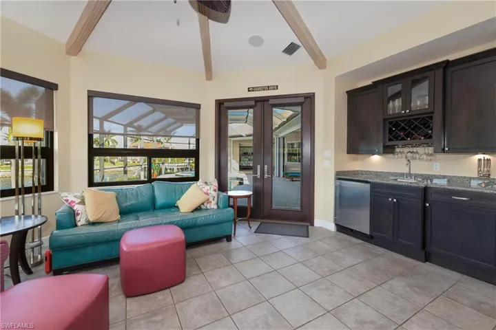 Tiled living room featuring lofted ceiling with beams and indoor wet bar