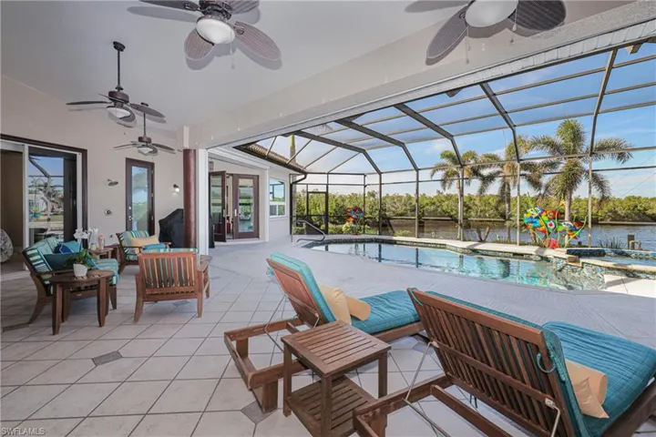 View of pool with glass enclosure, a water view, an outdoor hangout area, and a patio