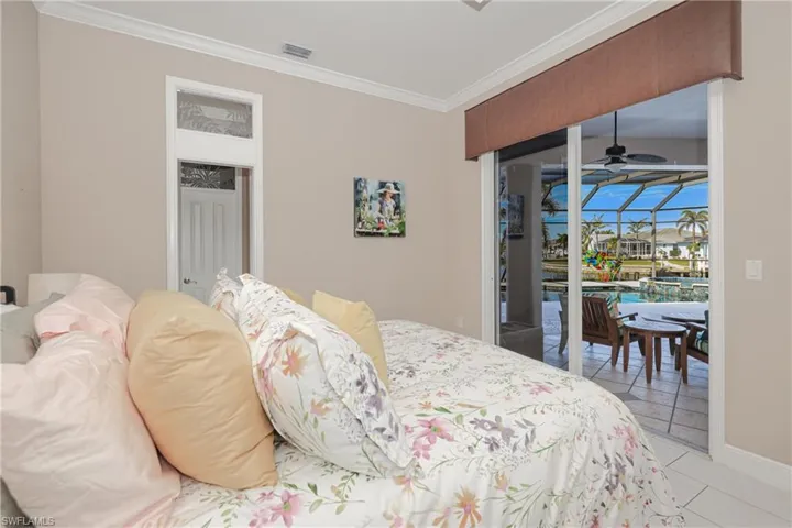 Bedroom featuring access to exterior, light tile patterned floors, and ornamental molding