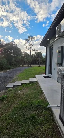View of grassy yard featuring a patio and view of scattered trees