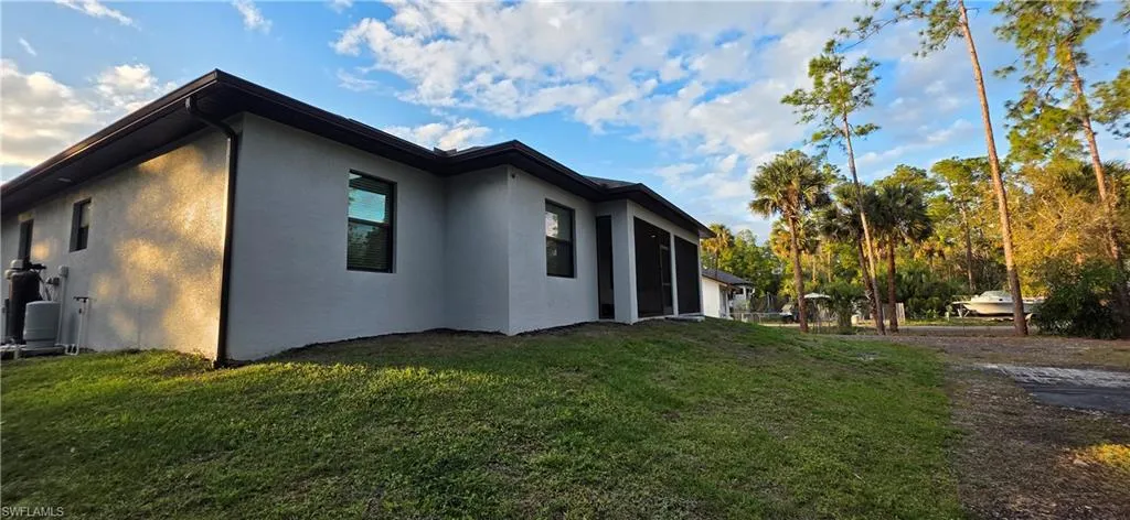 View of side of property featuring stucco siding, a lawn, and a sunroom