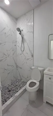 Full bathroom with a marble finish shower, vanity, and light marble finish floors