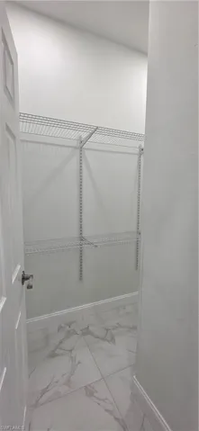 Spacious closet featuring light marble finish floors