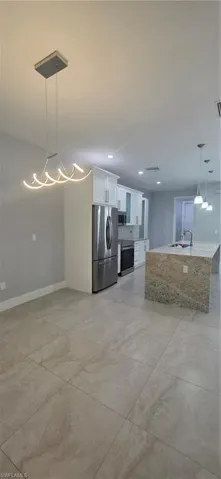 Kitchen with decorative light fixtures, white cabinetry, a kitchen island with sink, appliances with stainless steel finishes, and recessed lighting