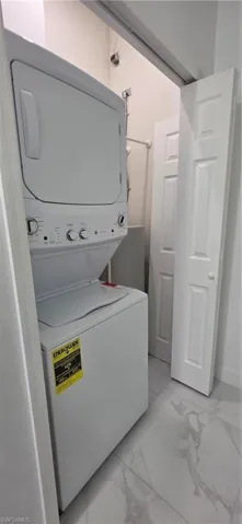 Laundry room featuring light marble finish floors and estacked washer and dryer