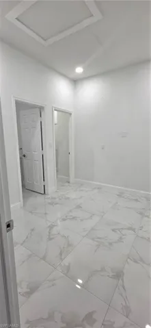 Empty room featuring baseboards and attic access