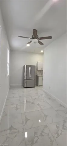 Unfurnished room featuring ceiling fan and light marble finish flooring