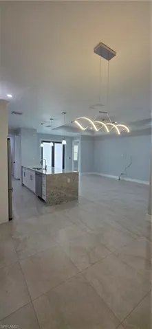 Unfurnished living room featuring baseboards and a sink