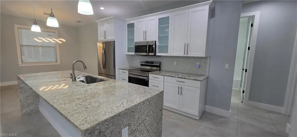 Kitchen featuring light stone countertops, appliances with stainless steel finishes, and white cabinets