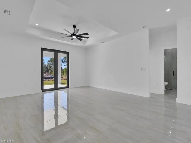 Empty room featuring french doors, ceiling fan, and a raised ceiling