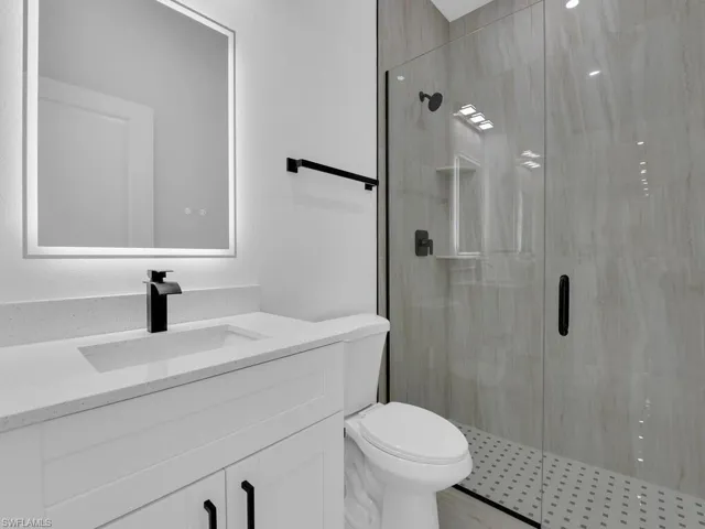 Bathroom featuring vanity, a shower with shower door, and toilet