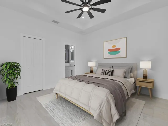Bedroom with ensuite bath, ceiling fan, and a tray ceiling