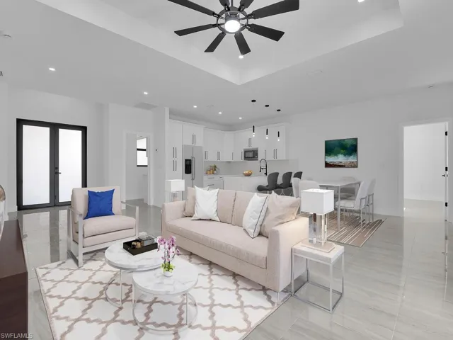 Living room with french doors, ceiling fan, and a raised ceiling