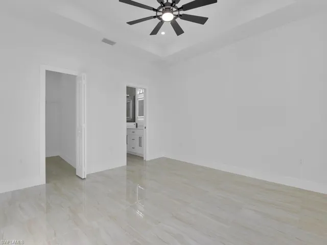 Empty room featuring ceiling fan and a tray ceiling