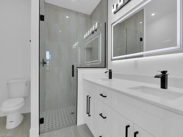 Bathroom featuring vanity, a shower with door, and toilet