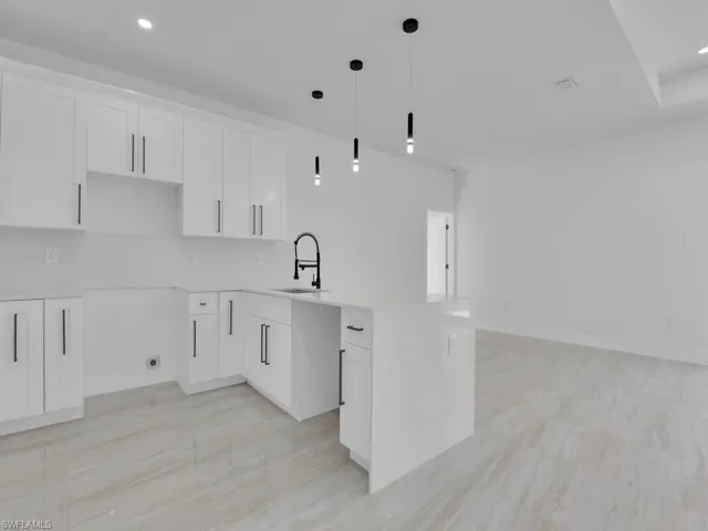 Kitchen with sink, pendant lighting, white cabinets, and decorative backsplash