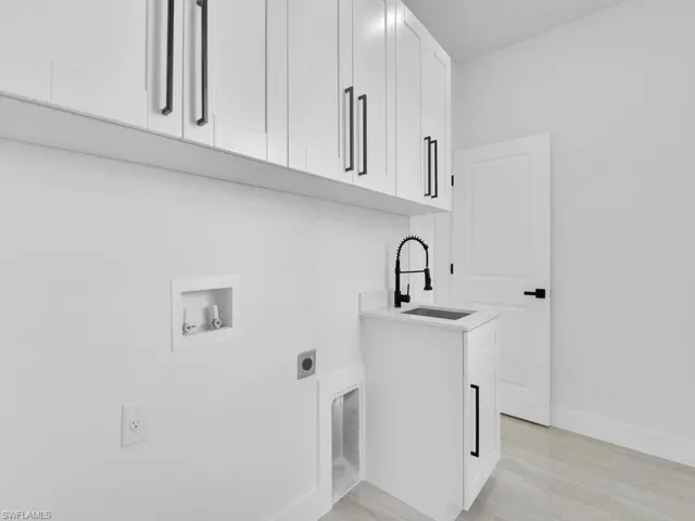 Washroom with cabinets, electric dryer hookup, sink, and hookup for a washing machine