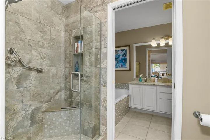 Full bath featuring a bath, vanity, a stall shower, and light tile patterned flooring
