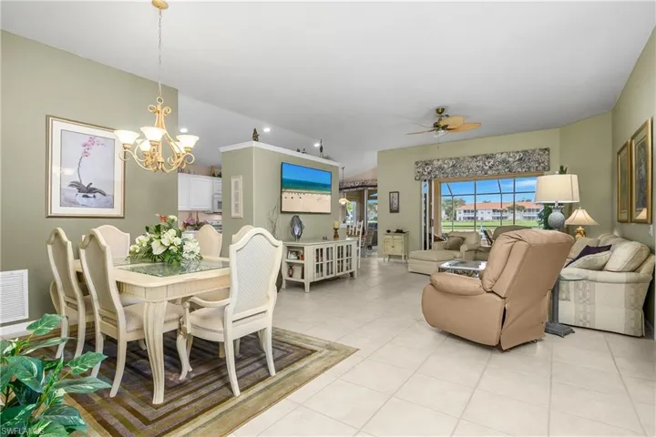 Dining space with a ceiling fan, light tile patterned flooring, vaulted ceiling, and a chandelier