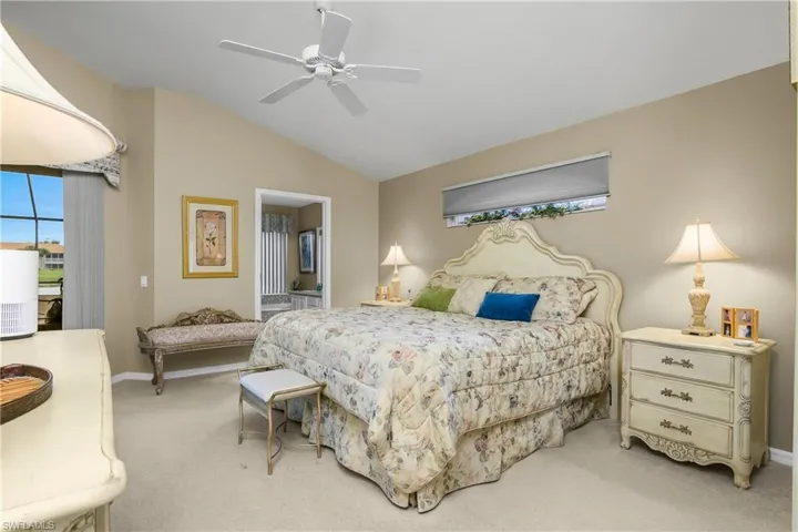 Carpeted bedroom with vaulted ceiling, a ceiling fan, and ensuite bathroom