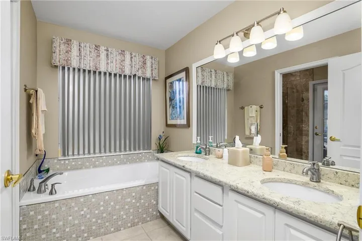 Bathroom with a garden tub, double vanity, and light tile patterned floors