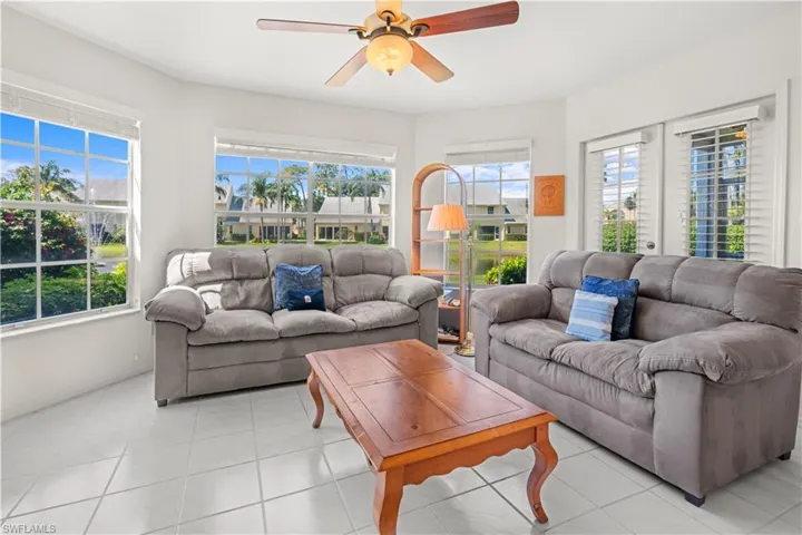 Living room with a wealth of natural light, ceiling fan, and light tile patterned flooring