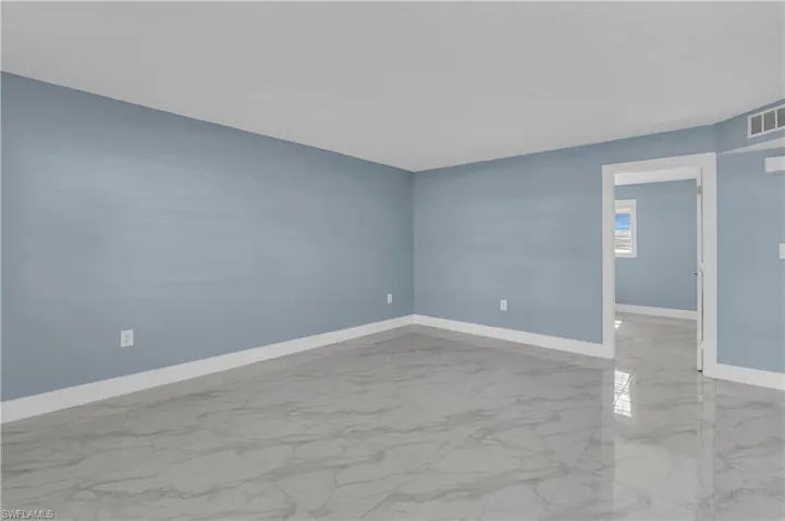 Spare room featuring marble finish flooring and baseboards