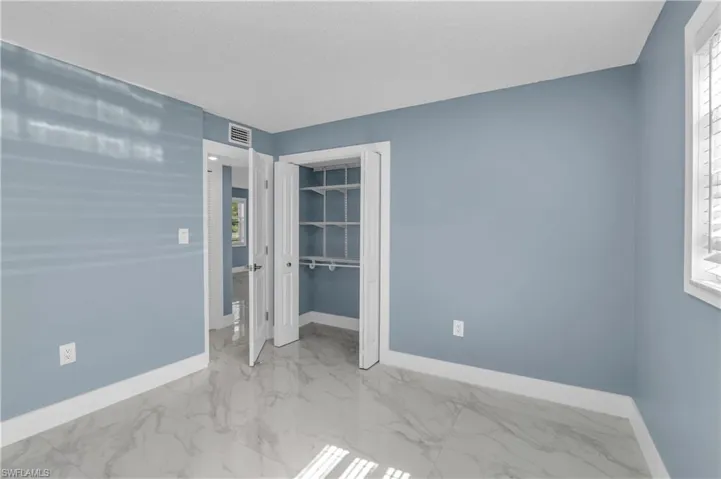 Unfurnished bedroom with light marble finish floors and a closet
