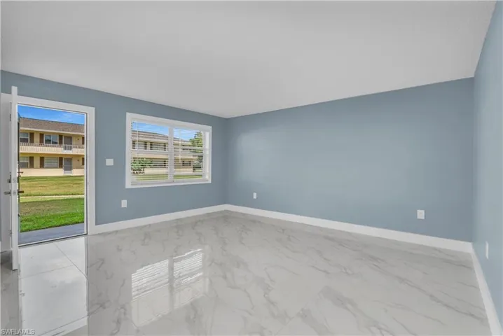 Spare room featuring light marble finish floors and baseboards