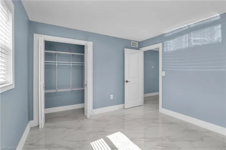 Unfurnished bedroom with light marble finish floors and a closet
