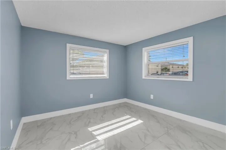 Spare room with light marble finish flooring, healthy amount of natural light, and a textured ceiling
