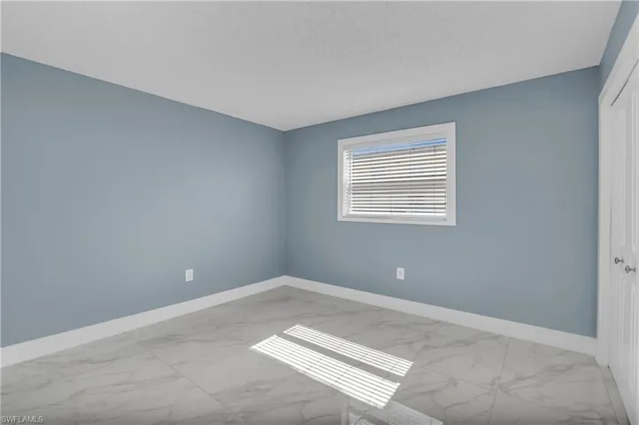 Empty room with marble look tiles and a textured ceiling