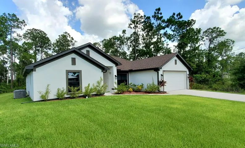 View of front facade featuring a garage and a front lawn