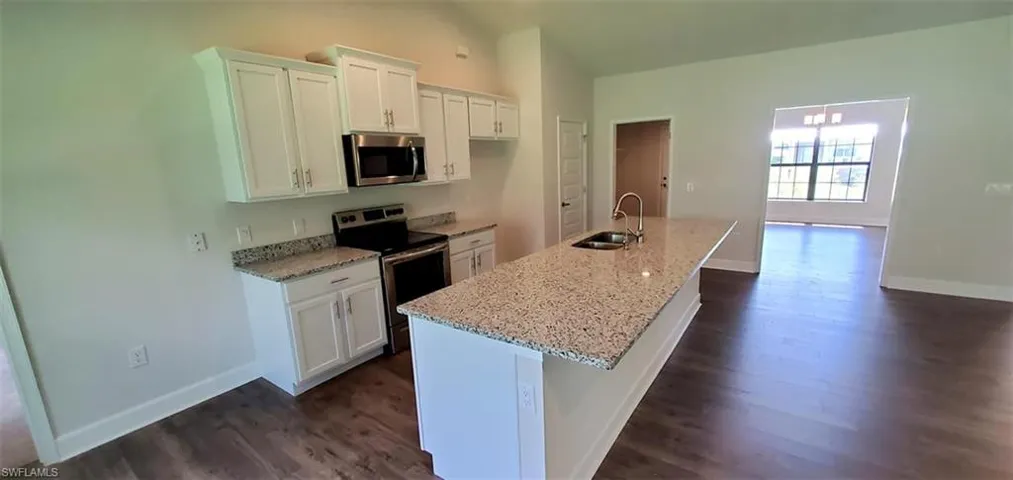 Kitchen featuring white cabinetry, stainless steel appliances, sink, dark hardwood / wood-style floors, and a kitchen island with sink